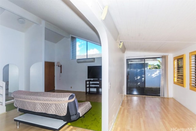 bedroom with multiple windows, lofted ceiling, and light wood-type flooring