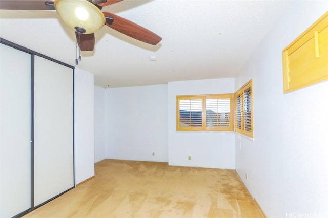 unfurnished bedroom featuring ceiling fan, light colored carpet, and a closet