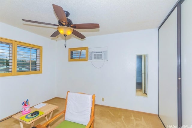 interior space featuring ceiling fan, light colored carpet, a textured ceiling, and a wall unit AC