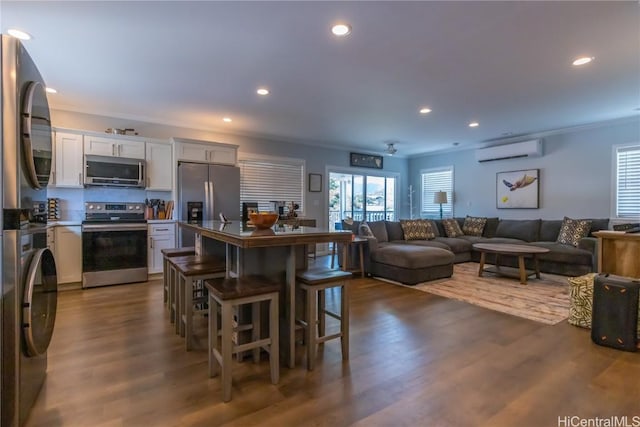 kitchen with dark wood-type flooring, a breakfast bar, white cabinetry, stainless steel appliances, and a wall mounted AC