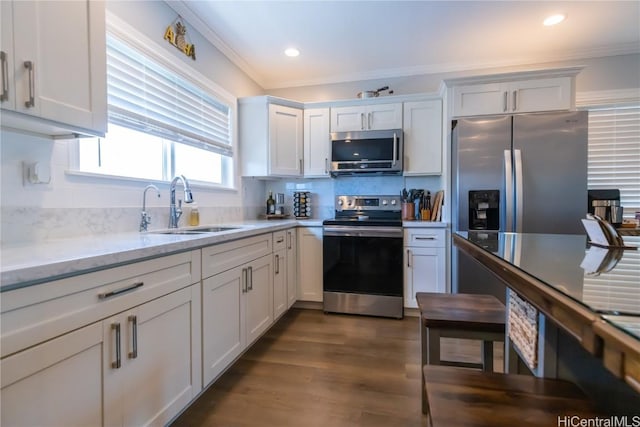 kitchen featuring sink, white cabinetry, ornamental molding, stainless steel appliances, and light stone countertops