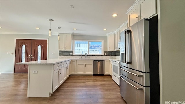 kitchen featuring white cabinetry, stainless steel appliances, kitchen peninsula, and sink