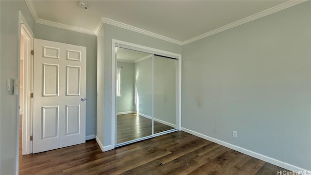 unfurnished bedroom featuring crown molding, dark wood-type flooring, and a closet