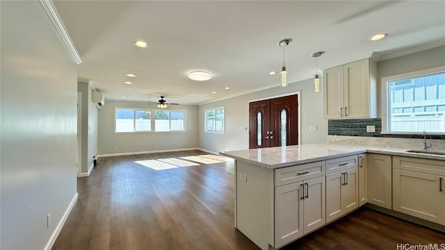 kitchen with pendant lighting, kitchen peninsula, sink, and light stone countertops