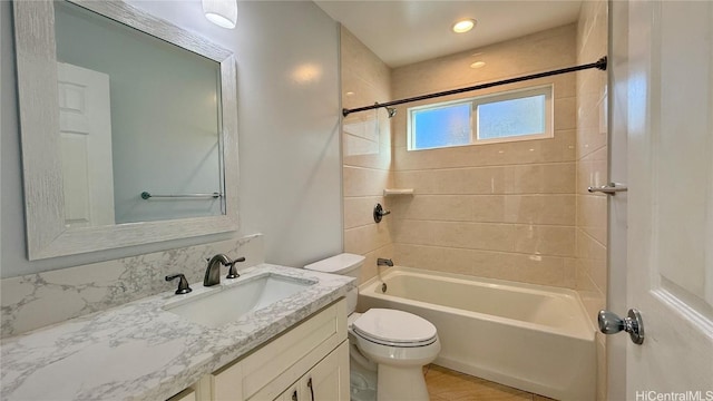 full bathroom featuring tiled shower / bath combo, vanity, and toilet