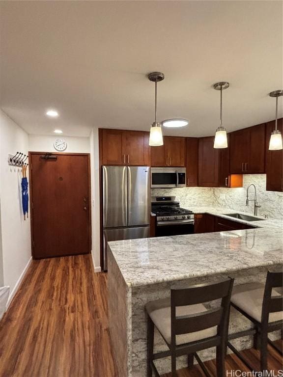 kitchen with pendant lighting, sink, dark hardwood / wood-style floors, kitchen peninsula, and stainless steel appliances