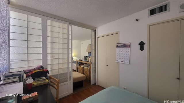 bedroom with a closet, a textured ceiling, and dark wood-type flooring