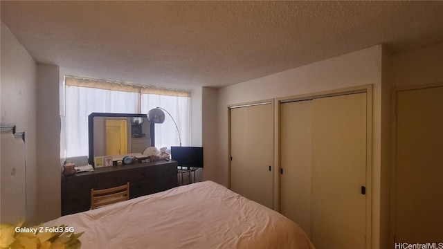 bedroom with a textured ceiling and multiple closets