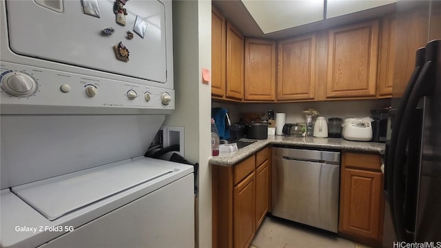 laundry area featuring light tile patterned floors and stacked washer and dryer