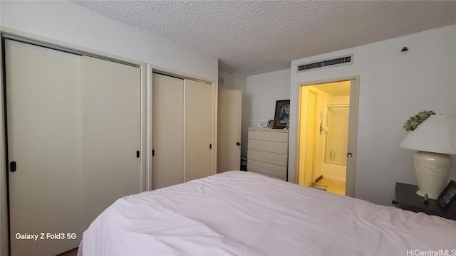 bedroom with multiple closets and a textured ceiling