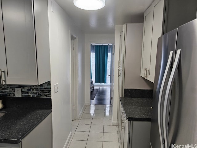 kitchen featuring white cabinets, stainless steel fridge, light tile patterned flooring, and tasteful backsplash