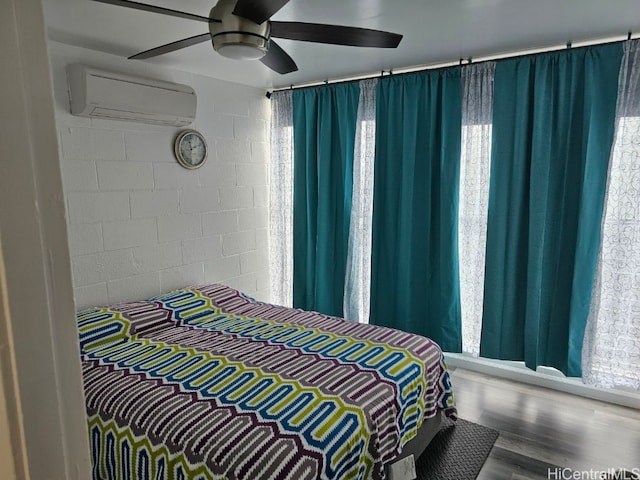 bedroom with a wall unit AC, ceiling fan, and hardwood / wood-style floors