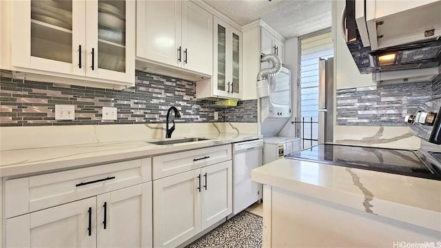 kitchen with white dishwasher, light stone counters, white cabinets, and sink