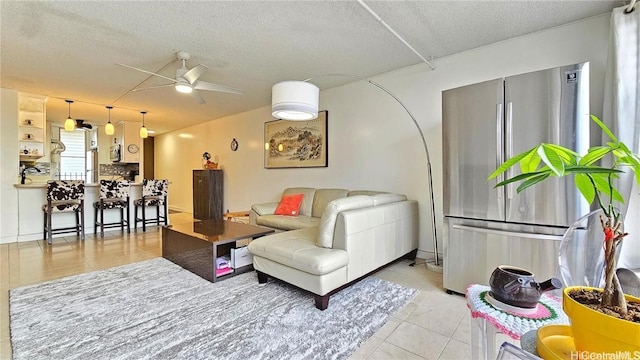 living room with ceiling fan, light tile patterned flooring, and a textured ceiling