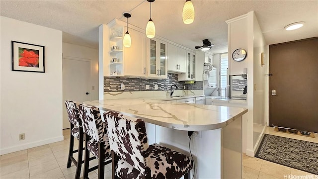 kitchen featuring decorative light fixtures, white cabinetry, a breakfast bar area, and kitchen peninsula