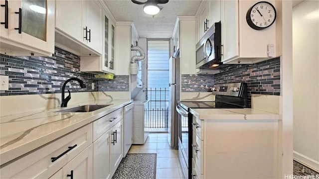 kitchen with light stone countertops, sink, stainless steel appliances, decorative backsplash, and white cabinets