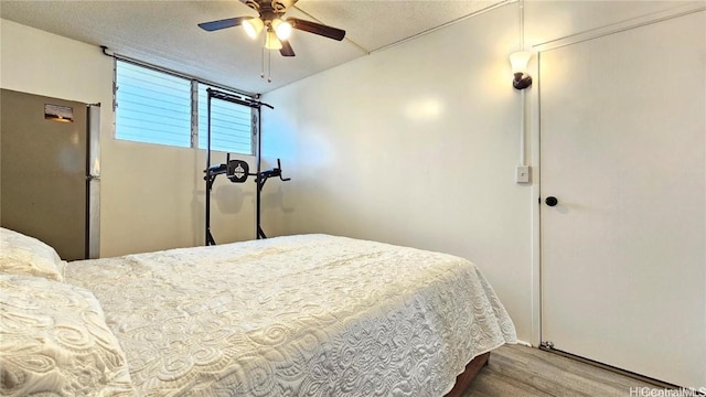 bedroom featuring ceiling fan, hardwood / wood-style floors, and a textured ceiling