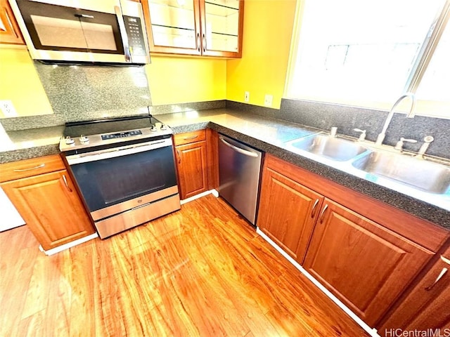 kitchen with backsplash, sink, light hardwood / wood-style floors, and appliances with stainless steel finishes