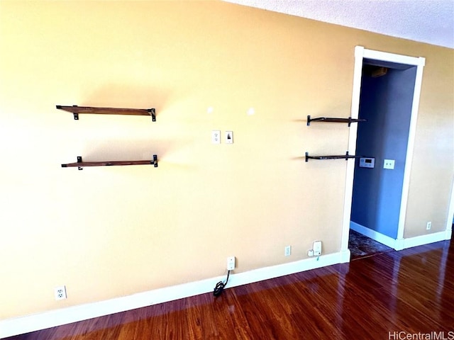 spare room featuring a textured ceiling and dark hardwood / wood-style floors