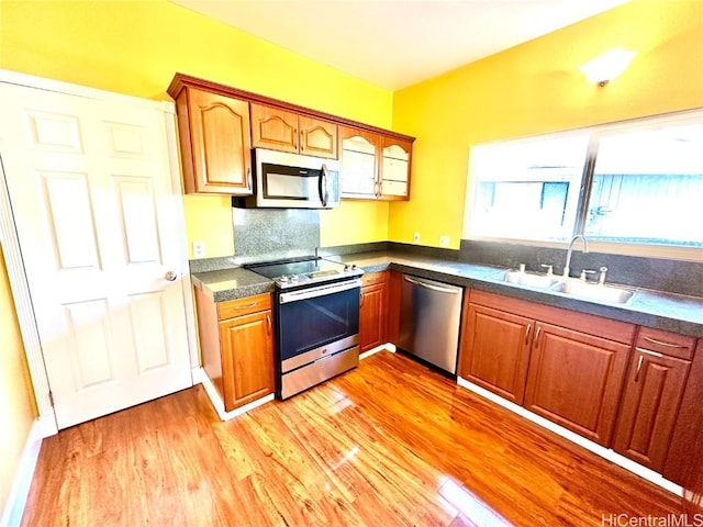 kitchen with tasteful backsplash, sink, stainless steel appliances, and light hardwood / wood-style floors