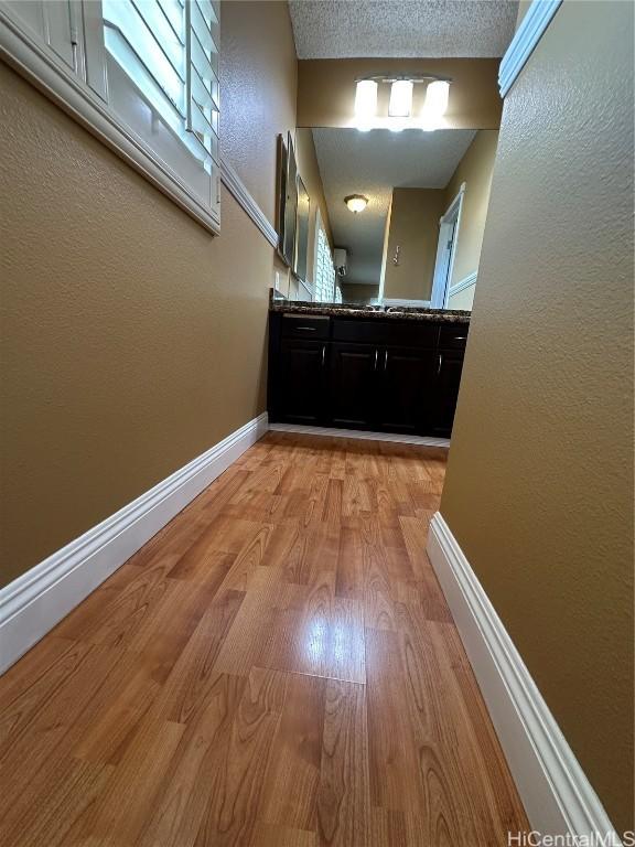 hall featuring light wood-type flooring and a textured ceiling