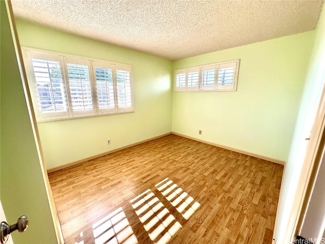 unfurnished room featuring light hardwood / wood-style floors and a textured ceiling