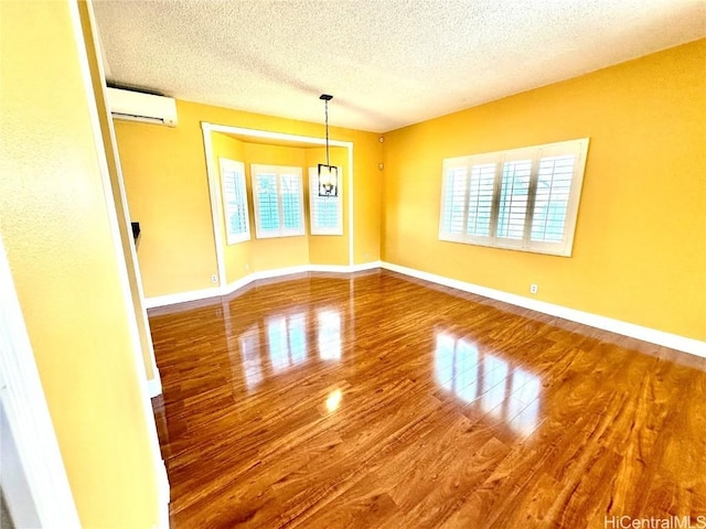 spare room with hardwood / wood-style flooring, a healthy amount of sunlight, a textured ceiling, and a wall mounted AC