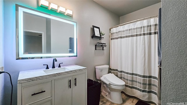 bathroom with hardwood / wood-style floors, vanity, a shower with shower curtain, and toilet