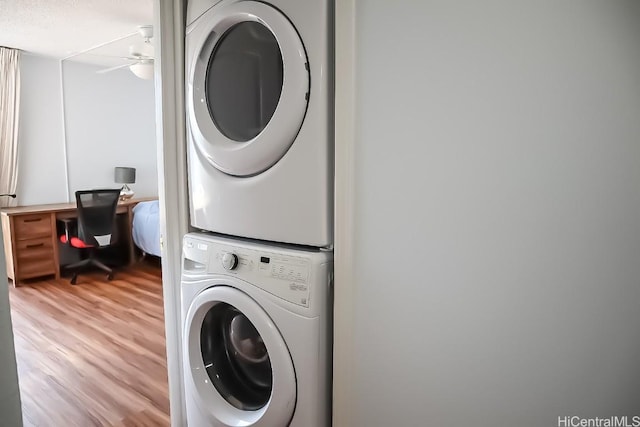 clothes washing area featuring a textured ceiling, ceiling fan, wood-type flooring, and stacked washer and clothes dryer