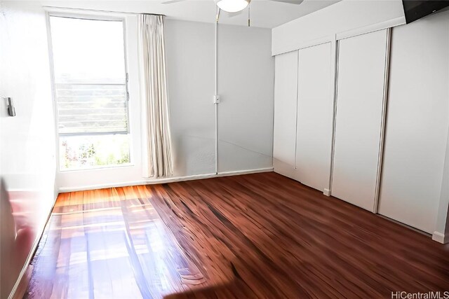 unfurnished bedroom featuring dark hardwood / wood-style floors, ceiling fan, and two closets