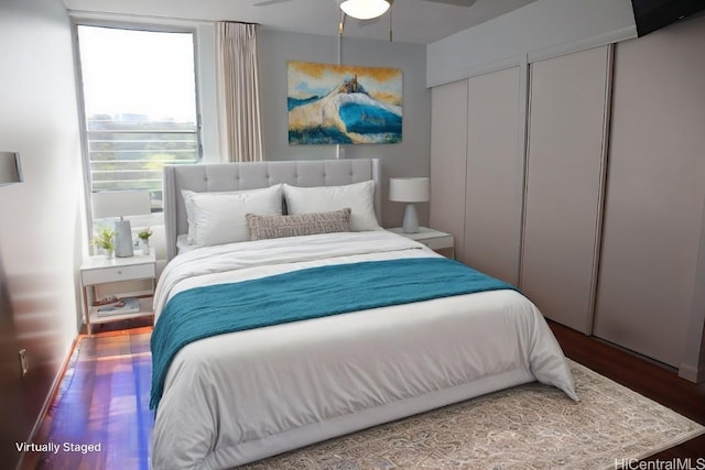 bedroom with hardwood / wood-style floors, two closets, and ceiling fan