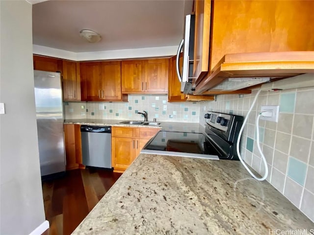 kitchen with light stone countertops, tasteful backsplash, stainless steel appliances, dark wood-type flooring, and sink