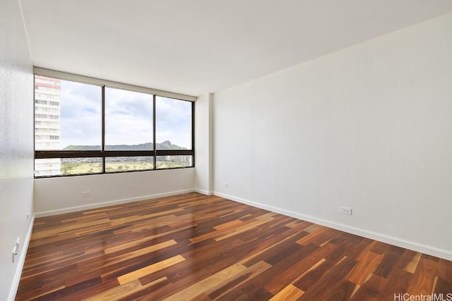 spare room with dark wood-type flooring and baseboards