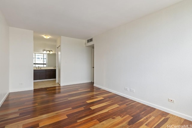 unfurnished room featuring baseboards, visible vents, and dark wood finished floors