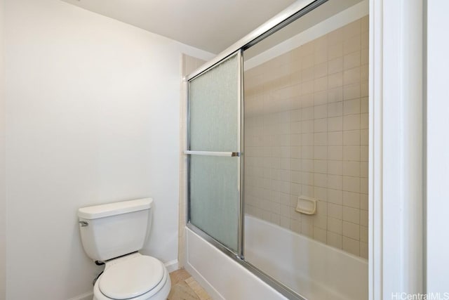 bathroom with bath / shower combo with glass door, toilet, and baseboards