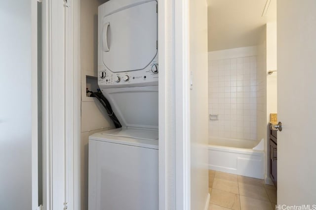 laundry room featuring laundry area, stacked washer / dryer, and light tile patterned flooring