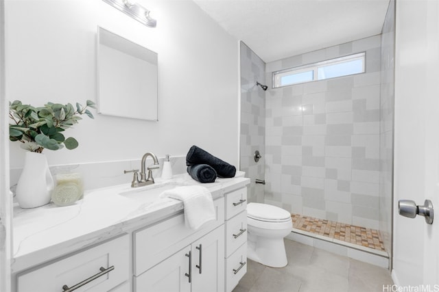 bathroom with tile patterned floors, vanity, toilet, and a tile shower