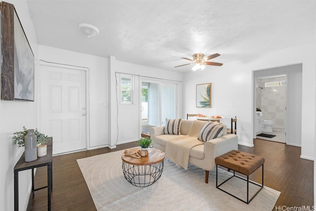 living room featuring a textured ceiling, dark hardwood / wood-style flooring, and ceiling fan