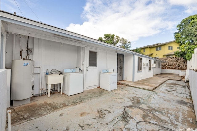 view of patio / terrace with washing machine and dryer, electric water heater, and sink