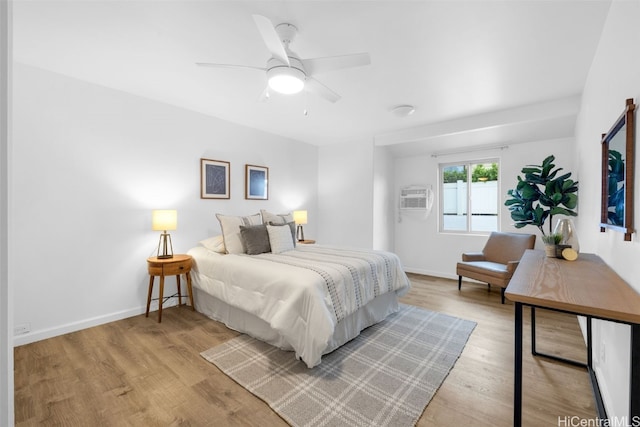 bedroom featuring light hardwood / wood-style flooring, ceiling fan, and an AC wall unit