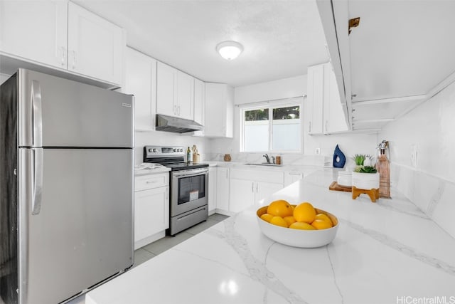 kitchen with appliances with stainless steel finishes, white cabinetry, and light stone counters