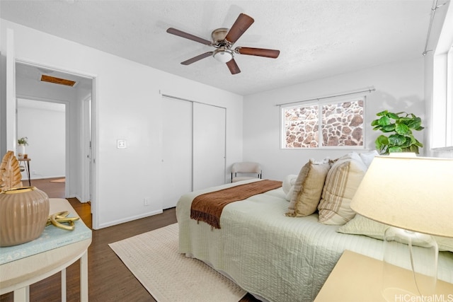 bedroom featuring a textured ceiling, a closet, dark hardwood / wood-style floors, and ceiling fan