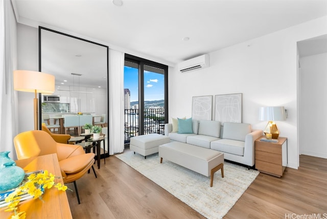 living room featuring an AC wall unit, light hardwood / wood-style flooring, and a wall of windows