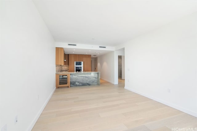 unfurnished living room with light hardwood / wood-style flooring and beverage cooler