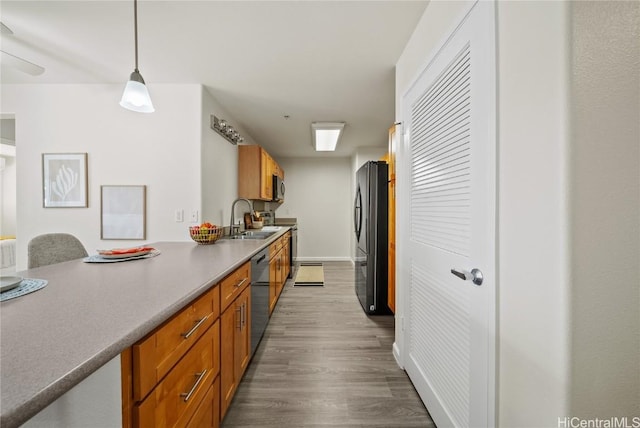 kitchen with decorative light fixtures, sink, appliances with stainless steel finishes, and light hardwood / wood-style flooring