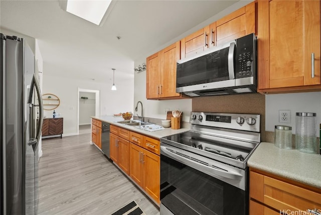 kitchen featuring decorative light fixtures, light wood-type flooring, stainless steel appliances, and sink