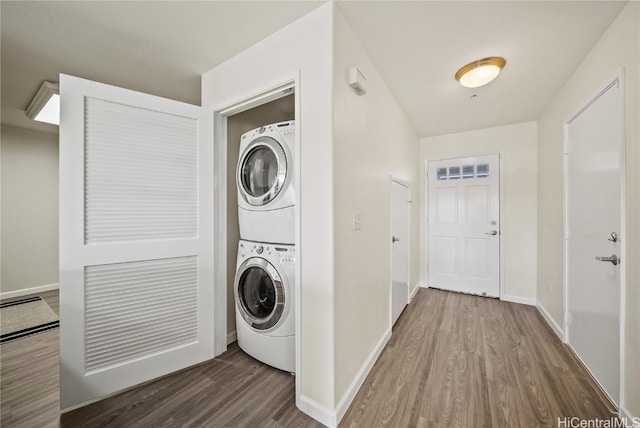 clothes washing area featuring hardwood / wood-style flooring and stacked washer / drying machine