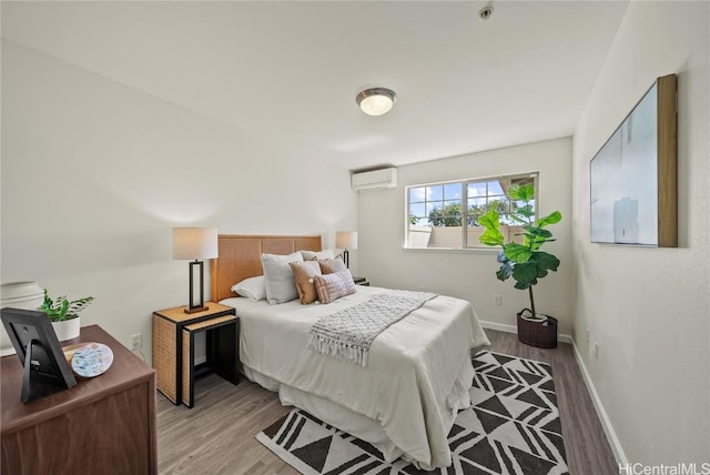 bedroom featuring light hardwood / wood-style floors and a wall unit AC