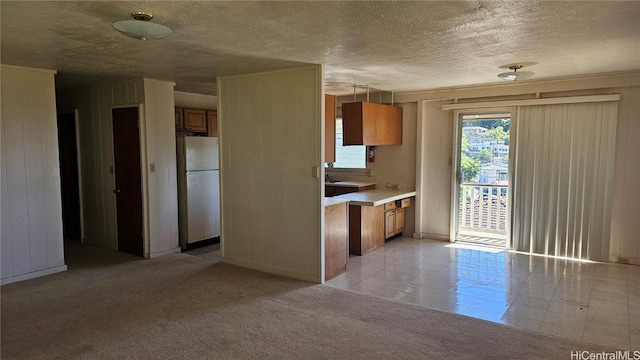 kitchen with a textured ceiling, white fridge, and light carpet