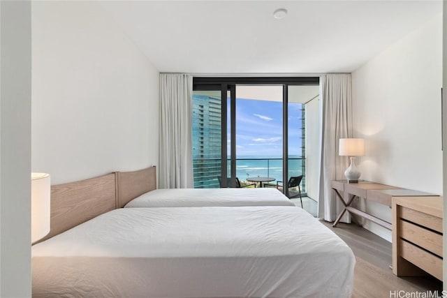 bedroom with access to outside, a wall of windows, a water view, and hardwood / wood-style flooring